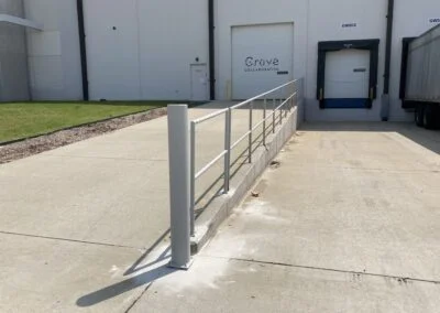 A concrete ramp with metal handrails leading to a commercial building entrance marked "grove coloratum" under a clear blue sky.